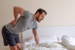 A man bent over, holding his lower back, experiencing sciatica